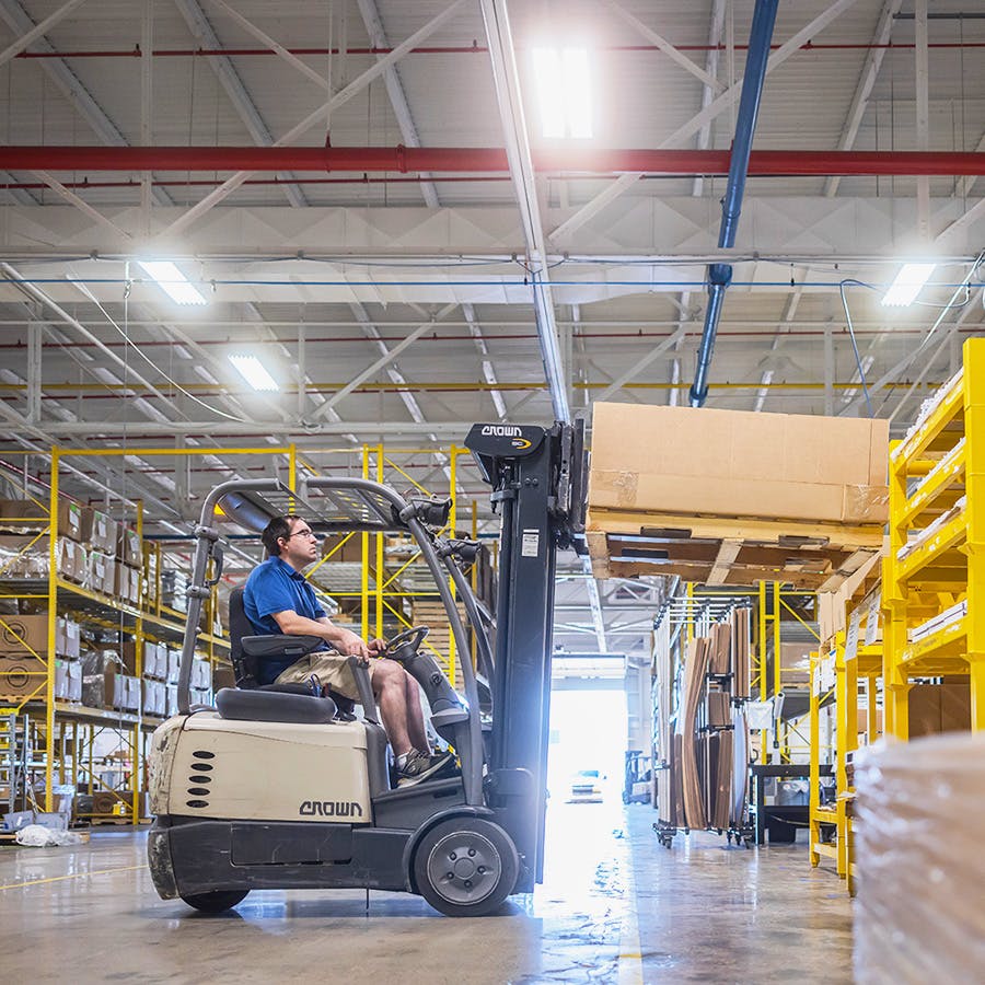 Production employee lifting a box with a forklift in a production facility 